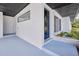 Covered entry showcasing a blue front door, white brick, and a small planter at 841 S Michigan Ave, Groveland, FL 34736