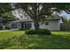 Home's front exterior with an inviting yard, mature tree, and screened-in porch at 841 S Michigan Ave, Groveland, FL 34736