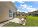 Green backyard with a patio and outdoor furniture, and sliding door entrance to home at 851 Evelynton Loop, The Villages, FL 32162
