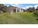 Lush green backyard with well-maintained lawn, patio seating, and sunroom at 851 Evelynton Loop, The Villages, FL 32162