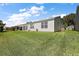 Spacious backyard with lush green lawn, sliding glass door, and well-maintained exterior of a single-story home at 851 Evelynton Loop, The Villages, FL 32162
