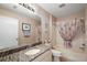 Bathroom with granite countertop, white cabinets, large mirror, and tub with shower at 851 Evelynton Loop, The Villages, FL 32162
