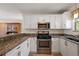 Well-equipped kitchen featuring white cabinets, stainless steel appliances, and granite countertops at 851 Evelynton Loop, The Villages, FL 32162