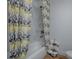 Bathroom with patterned shower curtain, white tiled walls, and fresh towels at 9144 Sw 156Th Pl, Dunnellon, FL 34432