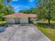 Exterior shot of a front entrance featuring an arched door, green grass, and a big tree at 9144 Sw 156Th Pl, Dunnellon, FL 34432