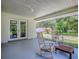 Covered porch area featuring rocking chairs and a view of the lush backyard, great for relaxing outdoors at 9144 Sw 156Th Pl, Dunnellon, FL 34432