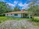 View of the back of the home with a covered porch surrounded by a green, tree-filled yard at 9144 Sw 156Th Pl, Dunnellon, FL 34432
