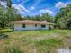 Back of house on a grassy lot features a red roof and a covered porch at 9144 Sw 156Th Pl, Dunnellon, FL 34432