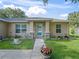 Close-up of a home's inviting entrance featuring a well-manicured lawn, and decorative flower pots at 9364 Se 164Th Pl, Summerfield, FL 34491
