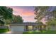 Charming single-story home with a well-maintained lawn, inviting facade, and two-car garage at sunset at 9364 Se 164Th Pl, Summerfield, FL 34491