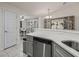 Bright kitchen area with views to the dining area features stainless dishwasher and grey cabinets and hardware at 9364 Se 164Th Pl, Summerfield, FL 34491