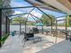 View of the screened patio with lounge chairs, table, and a grill, perfect for outdoor entertaining at 9364 Se 164Th Pl, Summerfield, FL 34491