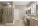 Bright bathroom with glass block shower, double vanity with marble countertops, and neutral tile flooring at 946 Isle Of Palms Path, The Villages, FL 32162