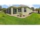 Back exterior view featuring a serene landscape with river rock, bushes, and a screened-in patio at 946 Isle Of Palms Path, The Villages, FL 32162