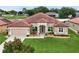 Inviting single-story home featuring a red tile roof, arched windows, and a lush green lawn at 10240 Kabana Blvd, Clermont, FL 34711
