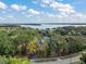 Expansive aerial view of a lakefront property surrounded by mature trees and blue sky, with outlined lot at 10303 Se Sunset Harbor Rd, Summerfield, FL 34491