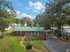 Aerial view of property featuring a brick home, metal carport, driveway and beautiful landscaping at 10303 Se Sunset Harbor Rd, Summerfield, FL 34491