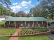 Charming brick home featuring a green metal roof, well-kept lawn and inviting front porch with rocking chairs at 10303 Se Sunset Harbor Rd, Summerfield, FL 34491