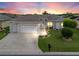 Charming single-story home with a three-car garage, manicured lawn, and inviting curb appeal at sunset at 11019 Se 170Th Lane Rd, Summerfield, FL 34491