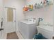 Functional laundry room featuring washer, dryer, ironing board, and shelving for ample storage at 11019 Se 170Th Lane Rd, Summerfield, FL 34491