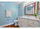 Bright bathroom featuring a white vanity, framed mirror, and a wooden-look vinyl floor at 1119 Pine Ave, Tavares, FL 32778