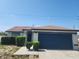 Charming single-story home with blue garage door, landscaped front, and bright blue skies at 112 Arlington Ct, Haines City, FL 33844