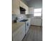 An efficient kitchen with white cabinetry, appliances, and a stainless steel sink under a window at 112 Arlington Ct, Haines City, FL 33844