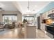 Spacious kitchen with granite countertops, stainless steel appliances, an island with seating, and views of the living room at 11215 Se 172Nd Place, Summerfield, FL 34491