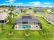 Aerial view of home with a screened-in pool, patio and lush green lawn with manicured landscaping and mature palms at 11215 Se 172Nd Place, Summerfield, FL 34491