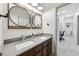 Bathroom with a double sink vanity with wood cabinets, round mirrors, and modern faucets at 11313 Little Nellie Dr, Clermont, FL 34711