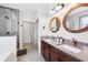 Modern bathroom with double sink vanity, wood-framed mirrors, and a frameless shower at 11313 Little Nellie Dr, Clermont, FL 34711