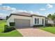 Attractive home exterior with a brick driveway, two-car garage, and manicured landscaping at 11313 Little Nellie Dr, Clermont, FL 34711