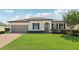 Charming one-story home with a well-manicured lawn, brick driveway, and elegant architectural details at 11313 Little Nellie Dr, Clermont, FL 34711