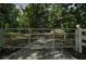 Gated driveway entrance leading to a charming home, surrounded by lush greenery and mature trees at 11495 Se 71St Terrace Rd, Morriston, FL 32668