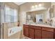 Elegant bathroom featuring a soaking tub, granite countertops, and vanity with wooden cabinets at 11601 Thacker Dr, Clermont, FL 34711