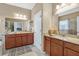 Bathroom featuring double sinks, granite countertops, wood cabinets, and decorative seashell jars at 11601 Thacker Dr, Clermont, FL 34711