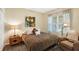 Cozy bedroom with a plush queen-sized bed, a window with sheer curtains, and warm, inviting decor at 11601 Thacker Dr, Clermont, FL 34711