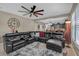 Spacious living room with a black leather couch, ceiling fan, and an open floor plan to the kitchen at 11601 Thacker Dr, Clermont, FL 34711