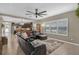 Open-concept living room featuring a large window, tile floors, and a cozy black leather sectional couch at 11601 Thacker Dr, Clermont, FL 34711