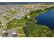 Aerial view showcases a community with sidewalks, a pond with dock, and pristine landscaping near a body of water at 124 Juno Dr, Groveland, FL 34736