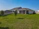 Expansive backyard featuring a screened patio, lush green grass, and ample space for outdoor activities at 124 Juno Dr, Groveland, FL 34736