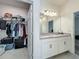 Bathroom view featuring walk-in closet, bright lighting over the double sink vanity and neutral finishes at 124 Juno Dr, Groveland, FL 34736