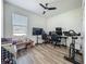 Bedroom with a ceiling fan, wood floors, a window, and home office space with multiple monitors at 124 Juno Dr, Groveland, FL 34736