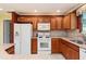 Charming kitchen with wood cabinets, white appliances, and decorative tile backsplash at 1282 Fort Lawn Loop, The Villages, FL 32162