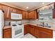 Cozy kitchen featuring wood cabinets, granite countertops, and white appliances for a classic look at 1282 Fort Lawn Loop, The Villages, FL 32162