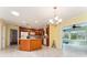 Open kitchen with an island, tile floors, wooden cabinetry, and a modern chandelier at 1282 Fort Lawn Loop, The Villages, FL 32162