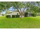 The yard offers mature tree coverage and a view of the home with a screened lanai at 12913 County Road 104B, Oxford, FL 34484