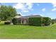 Wide backyard featuring mature green privacy hedges, a screened lanai, and lush green lawn at 12913 County Road 104B, Oxford, FL 34484