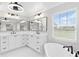 Bright bathroom featuring a dual vanity with white cabinets, black hardware, and a soaking tub near a window at 12913 County Road 104B, Oxford, FL 34484