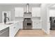 Modern kitchen with stainless appliances, white cabinets, quartz countertops, stainless vent hood, and modern fixtures at 12913 County Road 104B, Oxford, FL 34484